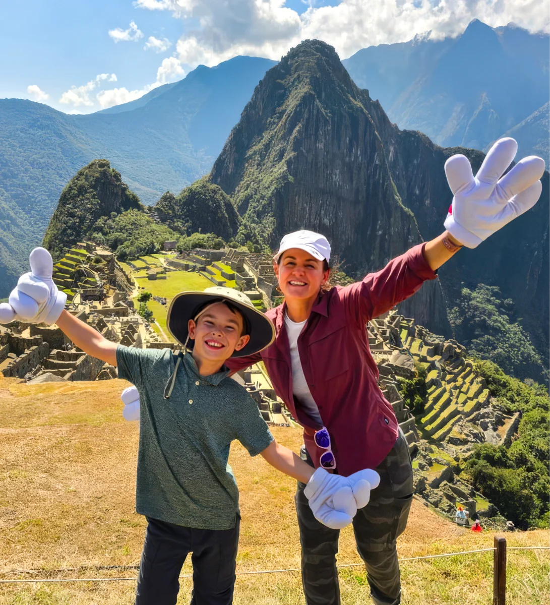 A boy and a woman pose with Mickey gloves at Machu Picchu