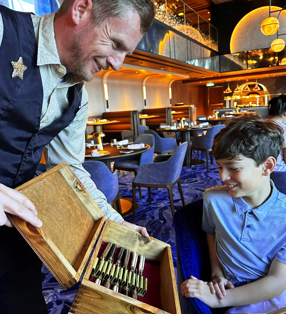 A chef shares a dining experience with a young guest