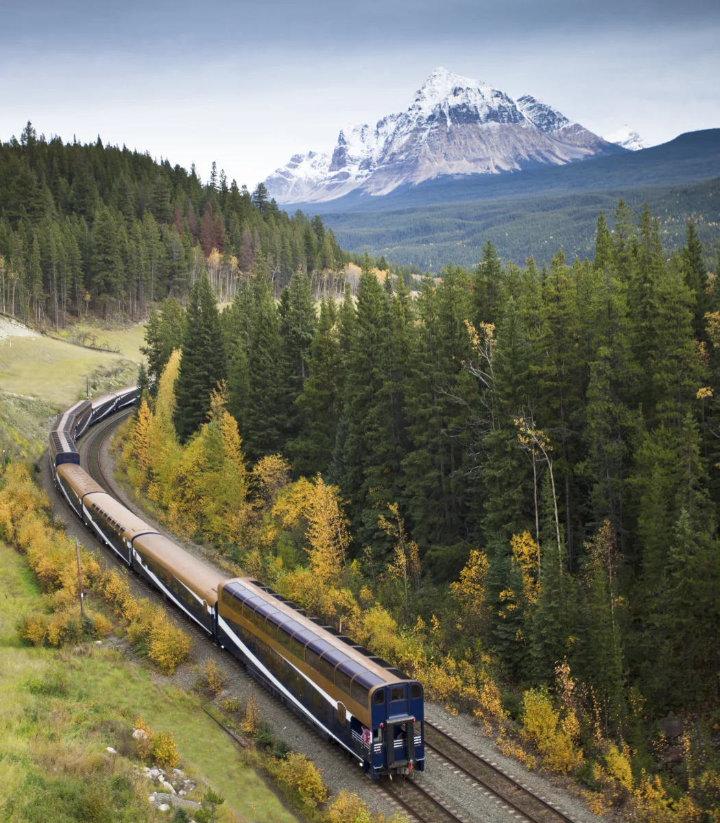 A passenger train winding through a mountain landscape